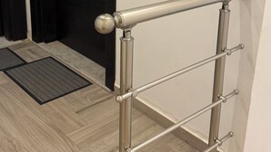 A metal handrail with horizontal bars, a door with a round handle, and a wooden floor with a patterned design. - Chic Luxury Appartement In The Heart Of La Marsa _ Walk to the Beach and Cafés (Marsa)