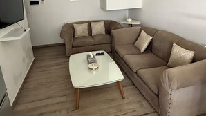 A modern living room with a sofa, coffee table, and a television. - Chic Luxury Appartement In The Heart Of La Marsa _ Walk to the Beach and Cafés (Marsa)
