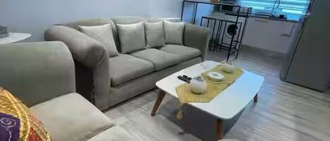 Una sala de estar moderna con un sofá, una mesa de centro y una cocina al fondo.
