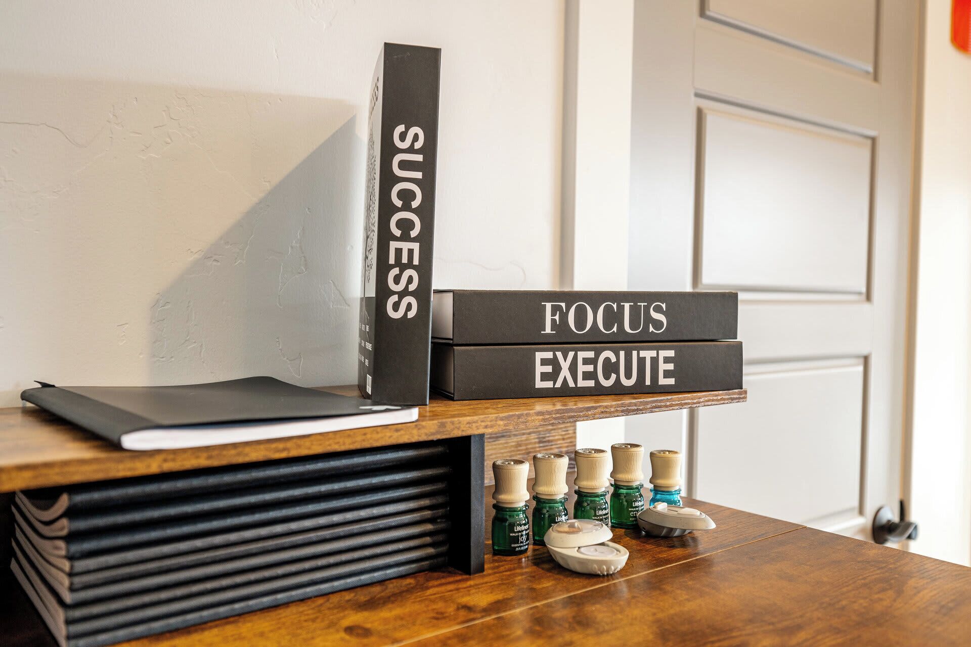 Un escritorio con una pila de libros, un cartel con las palabras 'SUCCESS', 'FOCUS' y 'EXECUTE', y una fila de botellas con etiquetas.