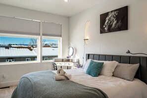 A bedroom with a bed, a bedside table, a mirror, and a painting on the wall.