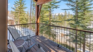 A wooden deck with metal chairs and a table, overlooking a snowy landscape with trees and mountains. - Westridge Ski-In/Ski-Out with Private Hot Tub (Breckenridge)