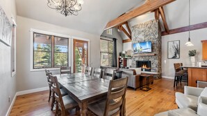 A spacious dining area with a wooden table and chairs, a stone fireplace, and a television mounted on the wall. - Westridge Ski-In/Ski-Out with Private Hot Tub (Breckenridge)