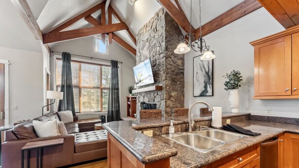 A modern kitchen with granite countertops, wooden cabinets, and a stone accent wall. - Westridge Ski-In/Ski-Out with Private Hot Tub (Breckenridge)