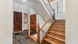 A staircase with wooden steps and metal railings, leading to a landing with a door and a window with blinds. - Westridge Ski-In/Ski-Out with Private Hot Tub (Breckenridge)