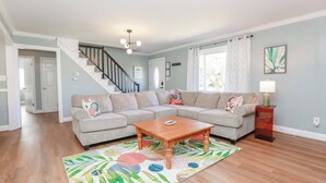 A living room with a sectional sofa, a wooden coffee table, and a patterned rug.