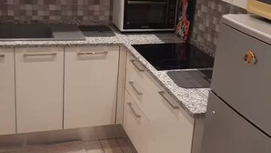 Una cocina moderna con armarios blancos, microondas, estufa y refrigerador.