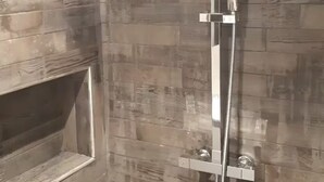 Ducha con revestimiento de pared de madera y un estante integrado.