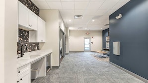Un couloir d’hôtel moderne avec un tapis gris, des murs blancs et un mur d’accent bleu foncé.