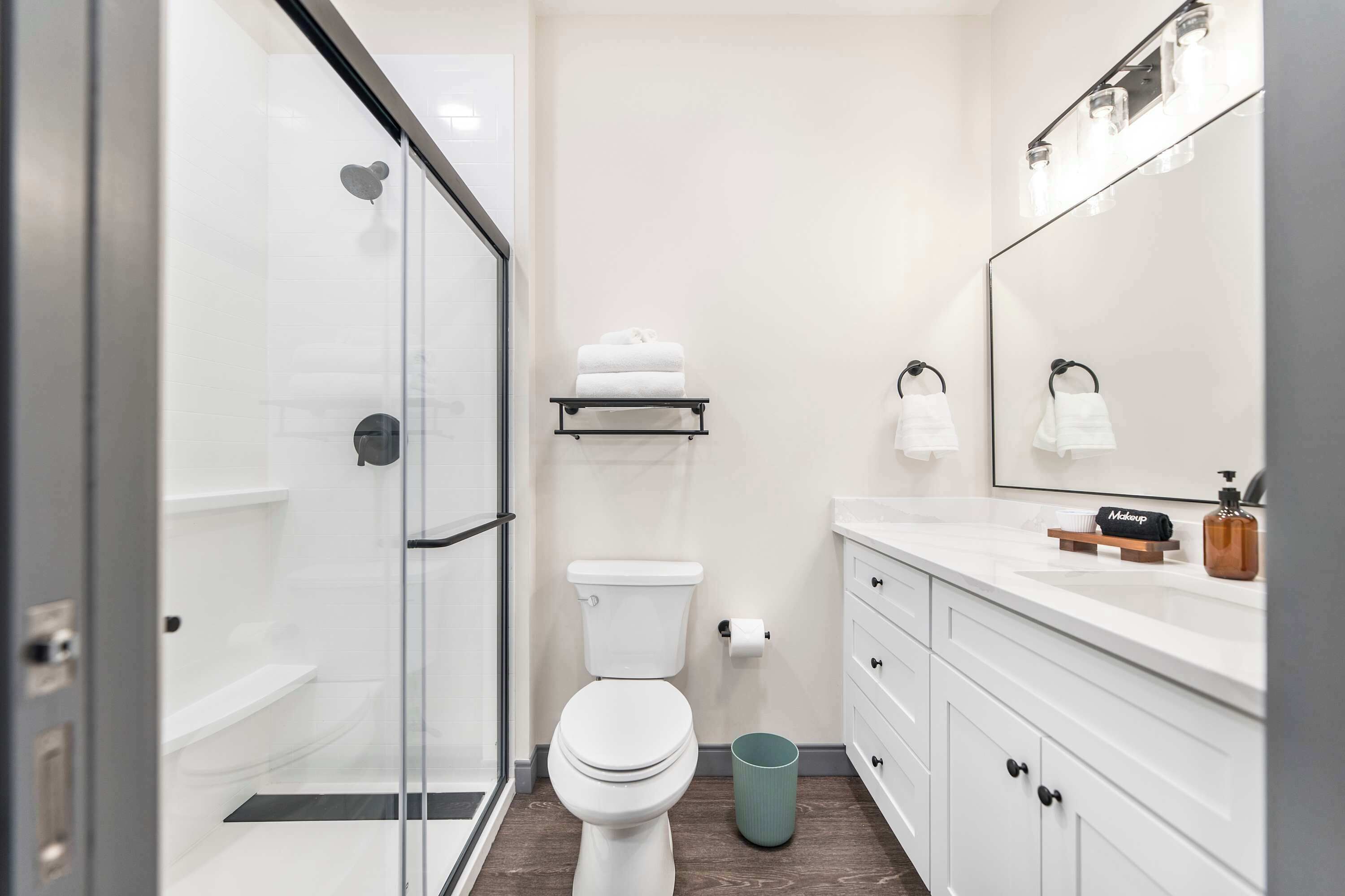 Un bagno moderno con box doccia in vetro, vaso igienico bianco e lavabo con specchio.