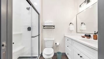 Un bagno moderno con box doccia in vetro, vaso igienico bianco e lavabo con specchio.