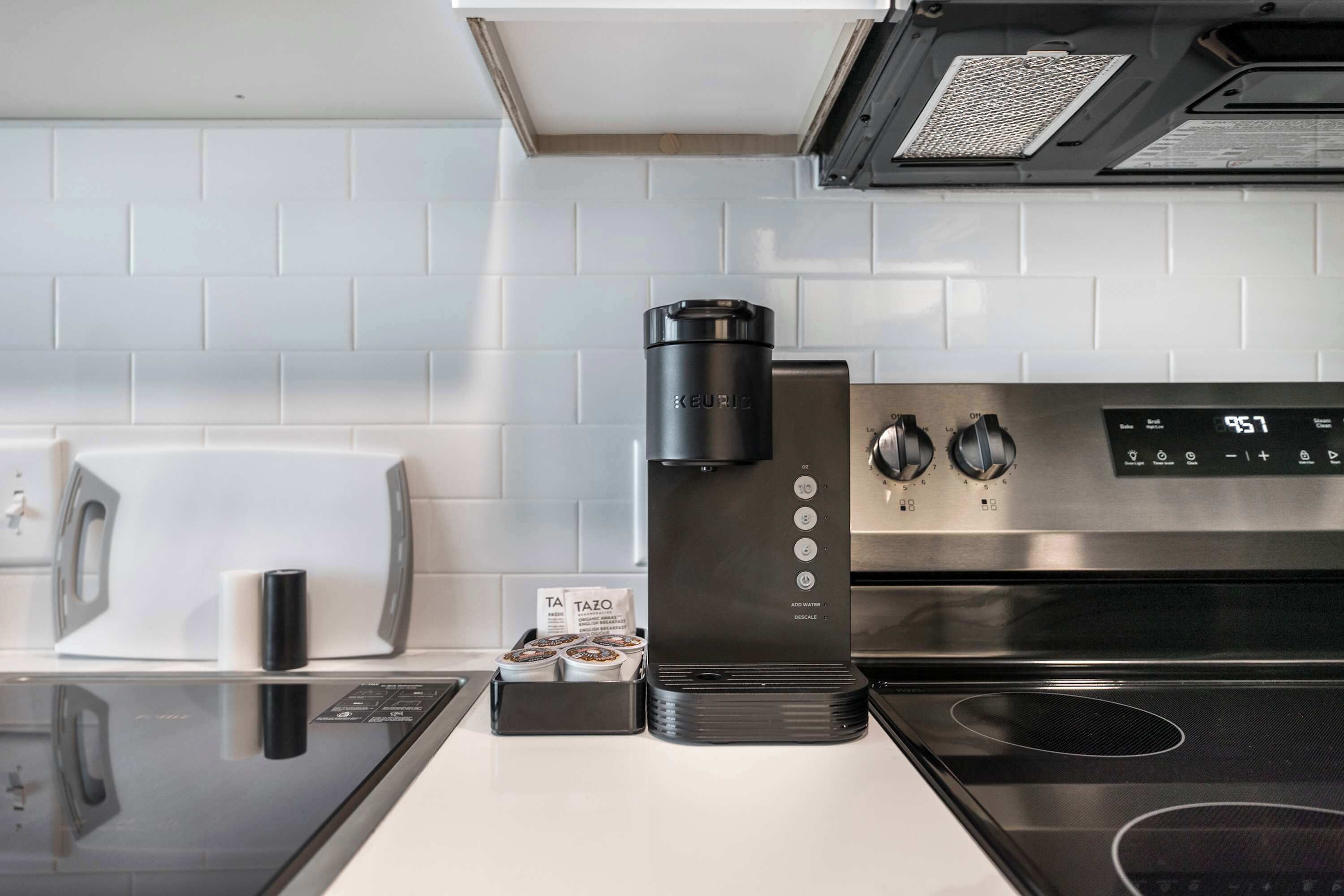A modern kitchen with a black coffee maker, a toaster, and a stainless steel stove.