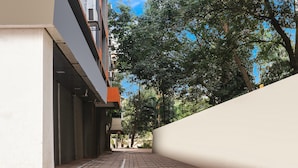 Un estrecho callejón con un sendero de ladrillo, una pared blanca a la derecha y un edificio con fachada gris a la izquierda.