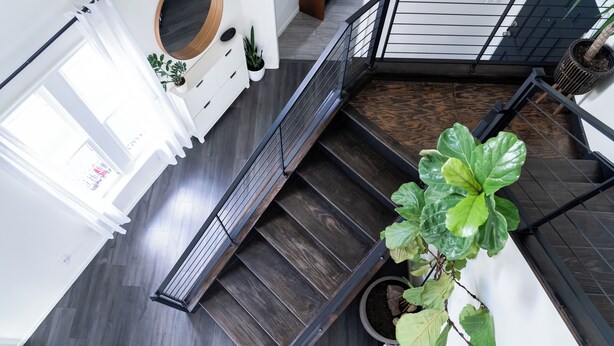 A modern staircase with a wooden finish, a black railing, and potted plants. - The New Hope Loft Walkable & Serene (New Hope)