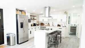 A modern kitchen with a stainless steel refrigerator, a built-in oven, and a central island with bar stools. - The New Hope Loft Walkable & Serene (New Hope)