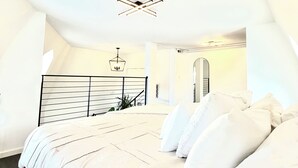A bedroom with a bed, a hanging light fixture, and a staircase. - The New Hope Loft Walkable & Serene (New Hope)