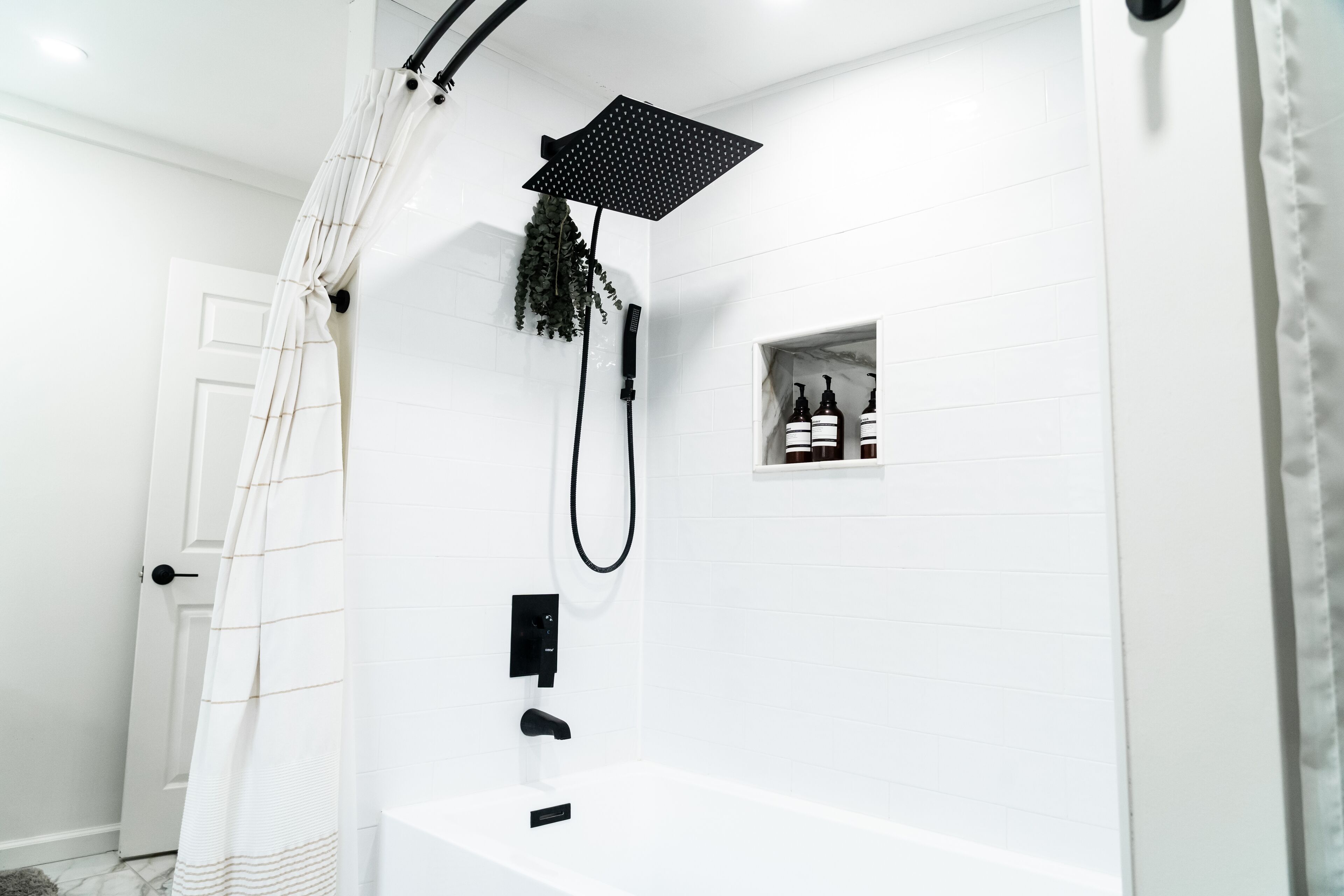 Une salle de bain moderne équipée d’une douche, d’une baignoire et d’une petite étagère où sont rangés les articles de toilette.