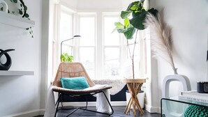 A cozy room with a wicker chair, a large plant, and a bookshelf. - The New Hope Loft Walkable & Serene (New Hope)
