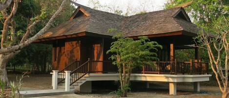 A two-story wooden house with a balcony and a covered porch.
