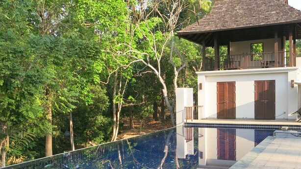 Ein modernes Haus mit Swimmingpool, umgeben von üppiger Vegetation.