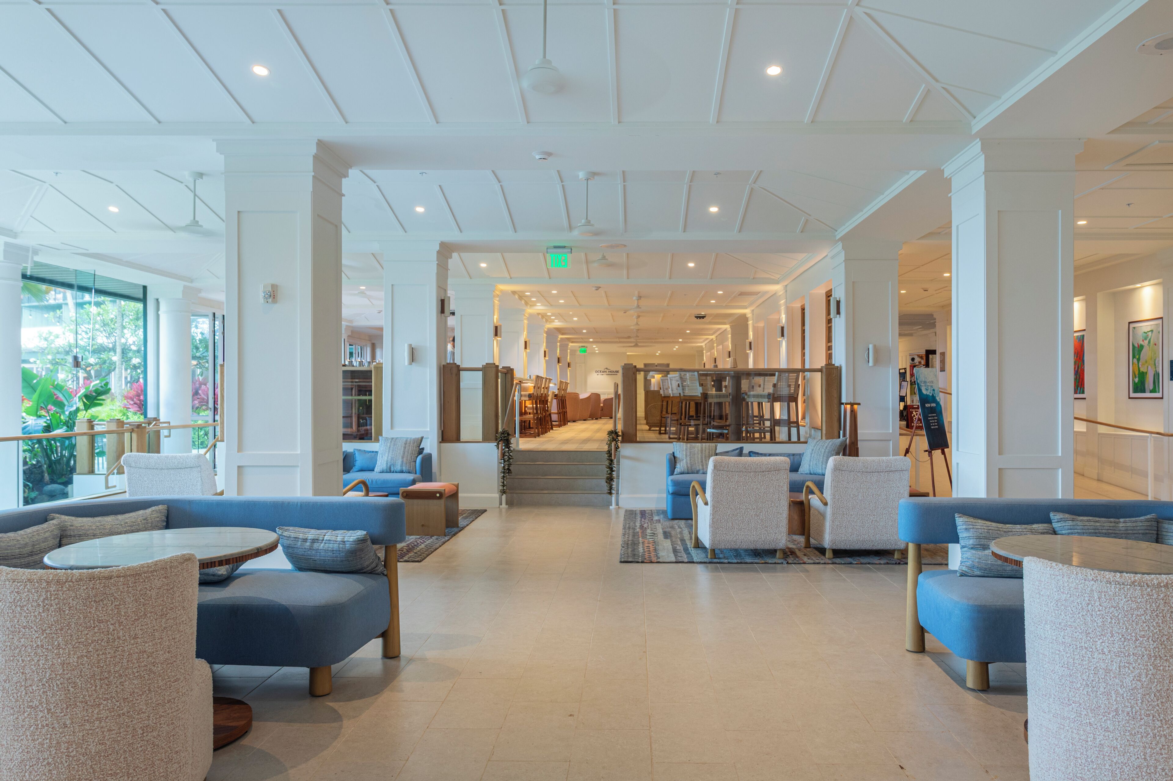 A spacious lobby with a high ceiling, modern furniture, and a view of the outdoors.