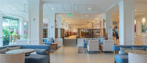 A spacious lobby with a high ceiling, modern furniture, and a view of the outdoors.