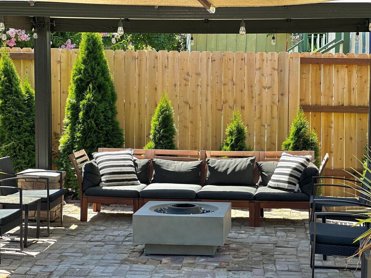 A patio with a wooden fence, a wooden bench, and a fire pit.
