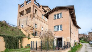 A two-story brick building with a prominent chimney and a small balcony.