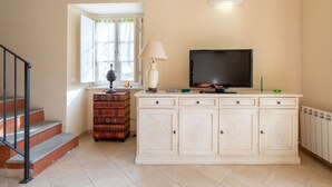 A living room with a staircase, a TV, a lamp, and a cabinet.