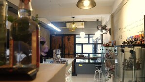 Een modern interieur met een bar, glazen vitrines en een groot raam dat natuurlijk licht binnenlaat.