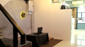 Een moderne hotellobby met een trap, een laptop op een tafel en een groot raam.