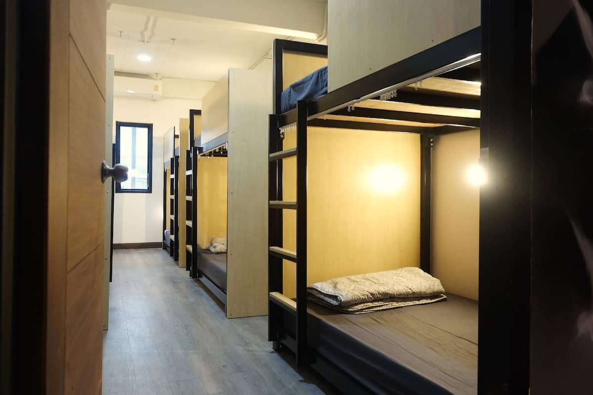 A corridor with bunk beds, wooden walls, and a window.