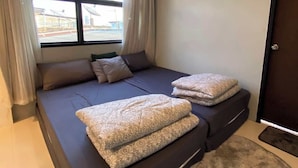 Een moderne slaapkamer met een groot bed, een raam met gordijnen en een deur.
