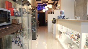 Een winkel met glazen vitrines vol beeldjes, een toonbank met koopwaar en een plafond met hangende lampen.