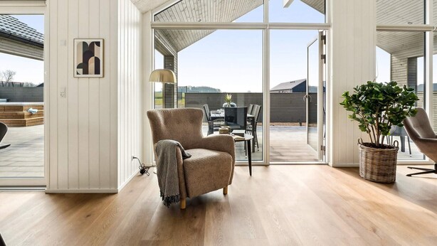 A spacious living area with a large sliding glass door leading to an outdoor patio. - 5 Star Holiday Home in Otterup (Otterup)