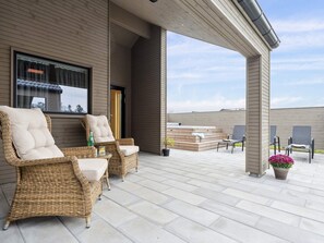 A covered outdoor patio with wicker furniture, a hot tub, and a view of the surrounding area. - 5 Star Holiday Home in Otterup (Otterup)