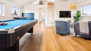 A pool table in a room with wooden floors, a television, and a staircase leading to an upper level. - 5 Star Holiday Home in Otterup (Otterup)