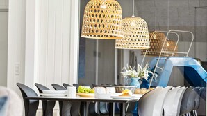 A dining area with a round table, black chairs, and wicker pendant lights. - 5 Star Holiday Home in Otterup (Otterup)