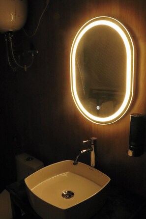 A bathroom with a modern sink, a mirror with a lighted frame, and a hand dryer. - Nilayam Resorts (Tehri)