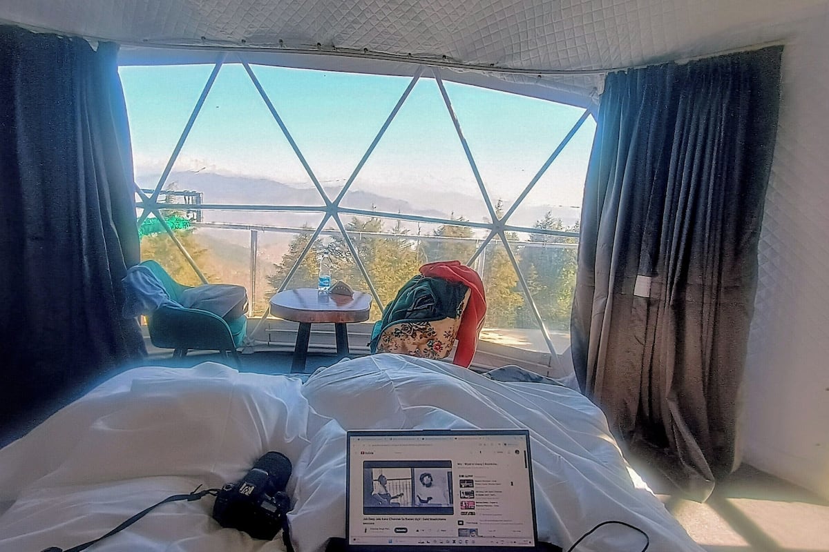 Una stanza con un letto, un portatile e vista su un balcone con sedie e un tavolo.