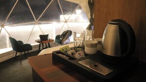 Ein Hotelzimmer mit einem Holztisch, einem Wasserkocher, Gläsern und einer Ablage mit Gegenständen.
