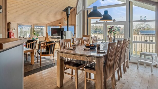 Un comedor amplio con una gran mesa y sillas, un televisor y vistas al exterior.