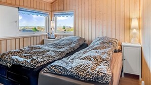 Habitación de cabaña de madera con dos camas, una ventana con vistas y una mesita de noche con lámpara.