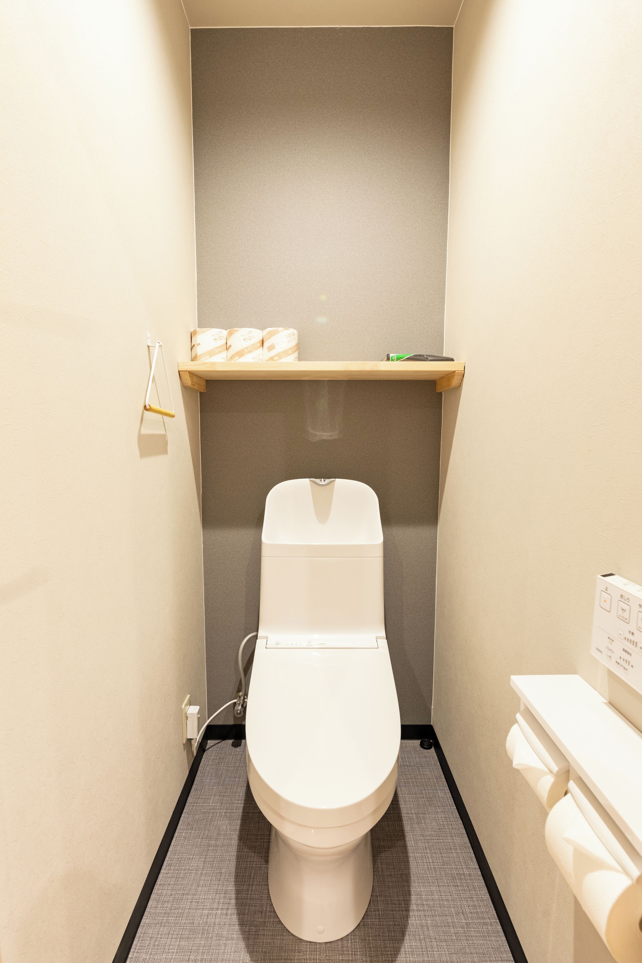 Un bagno piccolo e moderno, con il water, uno scaffale sopra il water e un dispenser per asciugamani.