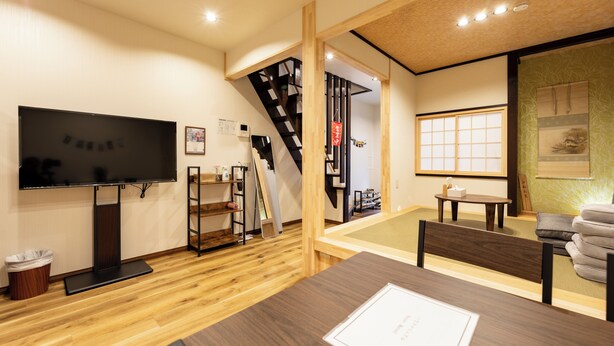 A modern interior with a wooden floor, a flat-screen TV, a staircase, and a traditional Japanese sliding door. - HIBIHIKARI Tsuruhashi (Osaka)
