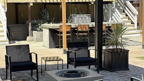 Eine Terrasse im Freien mit Grill, Stühlen und Feuerstelle.