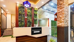 Un comptoir d’accueil avec une enseigne indiquant « Townhouse », un jardin vertical et un escalier menant à un niveau supérieur.