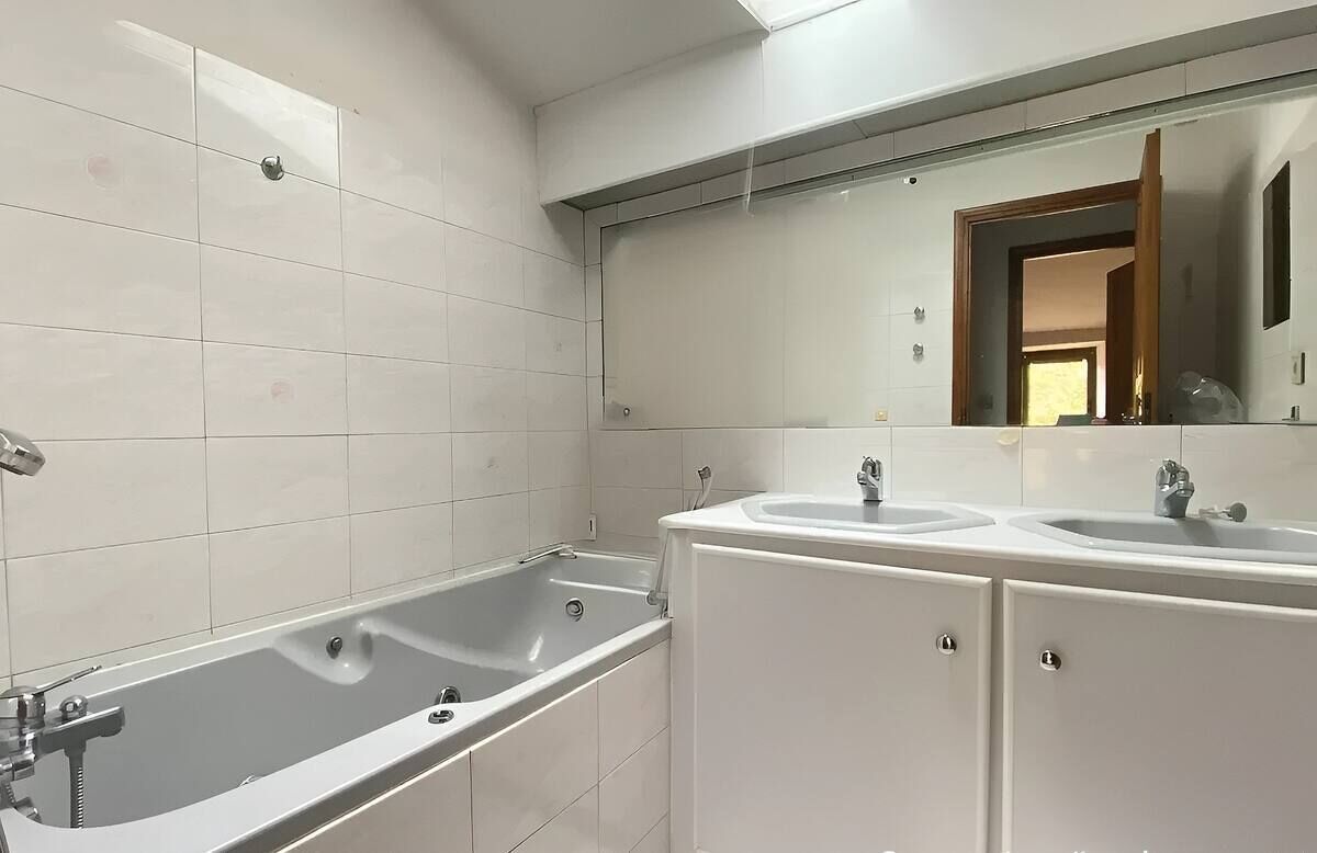 A bathroom with a bathtub, two sinks, and a large mirror.