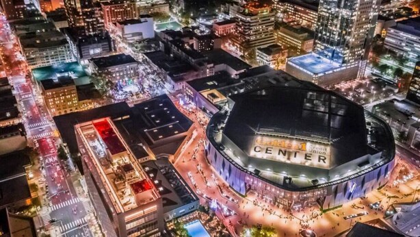 A large, circular building with a sign reading 'Golden 1 Credit Union CENTER' surrounded by a busy urban area with streets and other buildings. - King-Sized Luxury Furnished Space- Downtown Sac! (Sacramento)