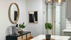 A modern kitchen with a marble countertop, a dining table with chairs, a potted plant, and a hanging light fixture. - King-Sized Luxury Furnished Space- Downtown Sac! (Sacramento)